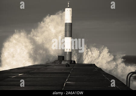 Wave breaking on jetty and beacon during storm at Aberystwyth in Wales.  With colour toning