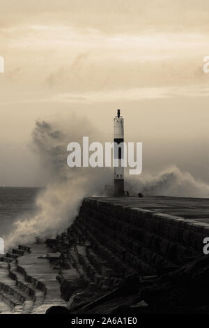 Wave breaking on jetty and beacon during storm at Aberystwyth in Wales.  With colour toning