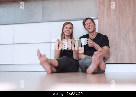 young couple sitting on the floor in new kitchen. Stock Photo