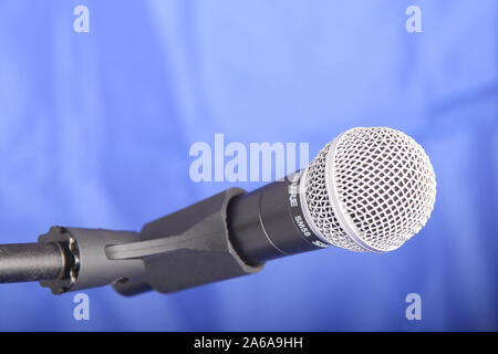 Shure SM58 microphone held in holder isolated on blue background with copy space Stock Photo