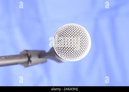 Shure SM58 microphone held in holder isolated on blue background Stock Photo