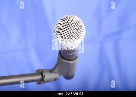 Shure SM58 microphone held in holder isolated on blue background with copy space Stock Photo