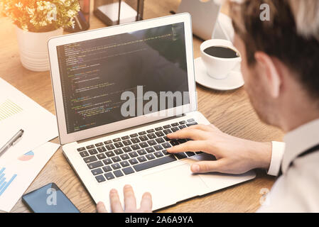Programmer working on code in office. Man working on laptop. Stock Photo