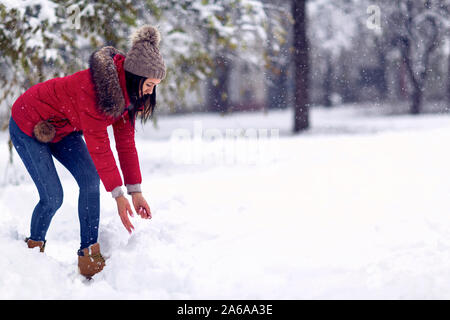 Girl playing with snow. Beautiful young woman in winter. Wintertime. Happy woman holds snowball in hands. Stock Photo