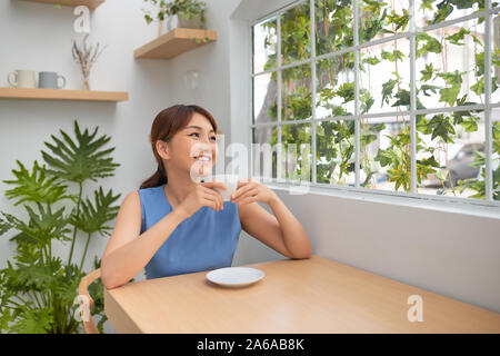 Beautiful Asian woman drinking coffee behind the green window Stock Photo