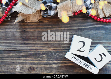 December 25 background. Wood calendar blocks with the date December 25th to mark Christmas Day with bokeh lights, black and white buffalo check and re Stock Photo