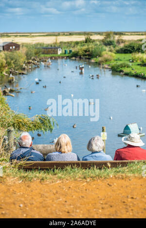 Elderly people enjoying the tranquility of Blakeney Conservation Duck Pond near the North Norfolk coast in East Anglia, England, UK.
