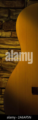 Acoustic guitar against a brick wall, illuminated by a beam of light Stock Photo