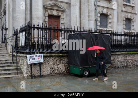 An elderly lady endures heavy rainfall on an autumn afternoon outside St. Martin-in-the-Fields church on Duncannon Street WC2, on 24th October 2019, in Westminster, London, England.
