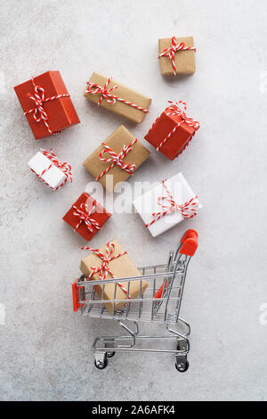 Gift boxes flying out of a shopping cart on light gray background. Seasonal sale and discount. Christmas preparation. Stock Photo