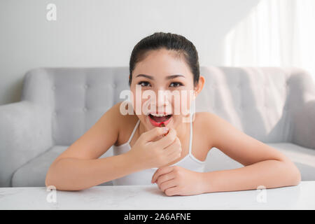 Portrait of beautiful young Asian female applying lipstick at home Stock Photo