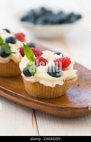 Delicious cupcakes with berries and fresh mint on wooden table Stock Photo
