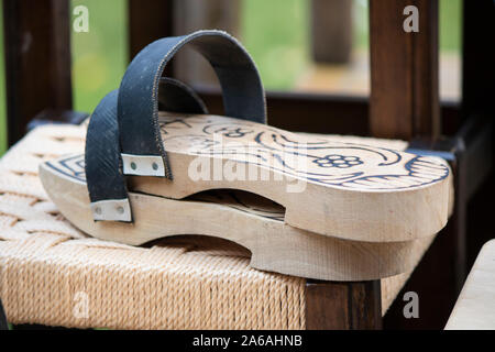 There are patterns on wooden slippers close-up. Bench on sale. Stock Photo