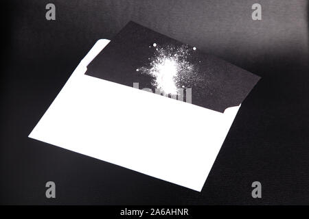 Ricin white powder being inserted in / removed from envelope on black card isolated on black leather background Stock Photo