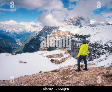 Young man in yellow jacket on the hill and snowy mountains Stock Photo