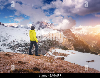 Young man in yellow jacket on the hill and snowy mountains Stock Photo