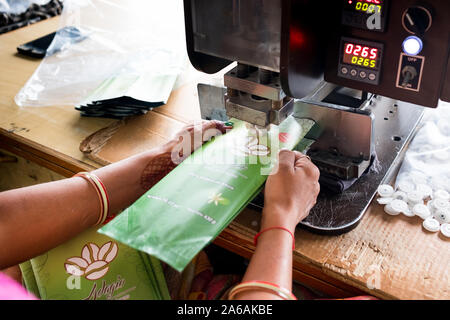 New delhi, India - 10 september 2019: close up of indian woman hands using industrial equipment inside packaging manufacturing plant Stock Photo