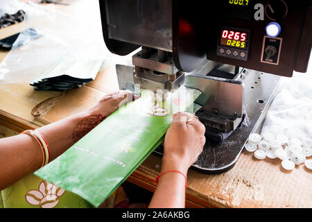 New delhi, India - 10 september 2019: close up of indian woman hands using industrial equipment inside packaging manufacturing plant Stock Photo