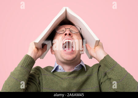 Clever guy holding abook on head being in panic. Stock Photo