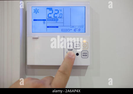 Adjusting room climate control with electronic device at home. Finger