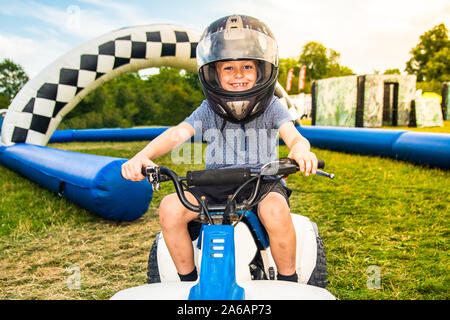 Little boy with ADHD, Autism, Aspergers Syndrome riding a quad bike smiling, laughing and having fun, crash helmet and visor on