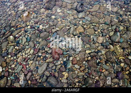 Texture of river pebbles in shallow water. Gravel under the river water. Stock Photo