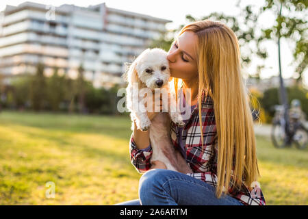 Beautiful woman spending time with her Maltese dog outdoor. Stock Photo