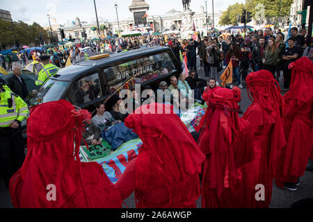 Extinction Rebellion climate change activist performance art troupe the Red Rebel Brigade wearing bright red costumes march silently as sites around Westminster are blocked on 9th October 2019 in London, England, United Kingdom. Extinction Rebellion is a climate group started in 2018 and has gained a huge following of people committed to peaceful protests. These protests are highlighting that the government is not doing enough to avoid catastrophic climate change and to demand the government take radical action to save the planet. Stock Photo