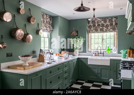Green paintwork in 1930s Art Deco style kitchen with wall mounted copper pots Stock Photo