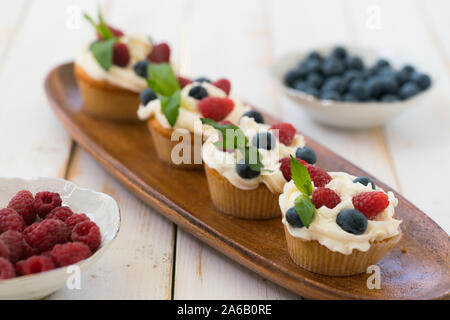 Delicious cupcakes with berries and fresh mint on wooden table Stock Photo
