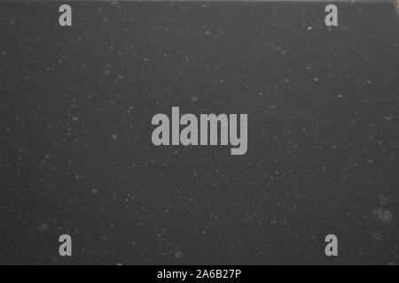 rain drops on the surface of water in a granite stone with graduated shade of black shadow and reflection of blue sky Stock Photo