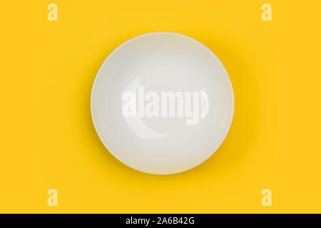 A deep white ceramic plate on a yellow  background Stock Photo