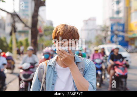 Asian man in the street wearing protective masks., Sick man with flu wearing mask and blowing nose into napkin as epidemic flu concept on the street. Stock Photo
