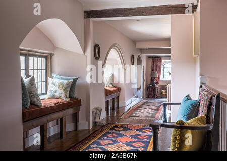 1930s Art Deco style arched window seats with patterned rugs in hallway. Stock Photo