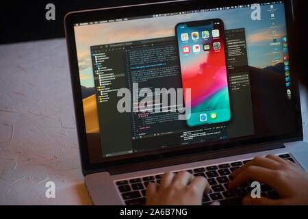 Bishkek, Kyrgyzstan - January 17, 2019: Man developer launches xcode software and ios simulator program to develop ios app on a MacBook Stock Photo