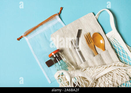 Set of reusable items for an eco-friendly lifestyle. Eco bag, glass bottle for water, metal tubes, wooden fork and spoon. Zero waste concept, plastic-free, organic, eco-friendly shopping Stock Photo