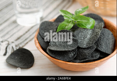 Black spicy potato chips in wooden  bowl Stock Photo