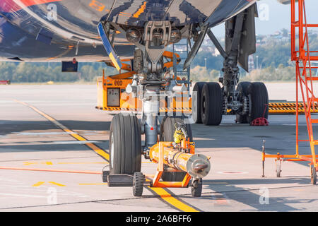 TUG carrier for huge airplane, trailer front landing gear pushback aerodrome tractor with airplane on the runway in airport Stock Photo