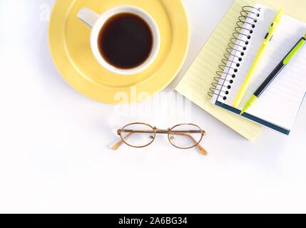 Coffee on yellow plate and notebooks with pen and pencil and eyeglasses in flat lay composition.  Horizontal format with room for text. Stock Photo