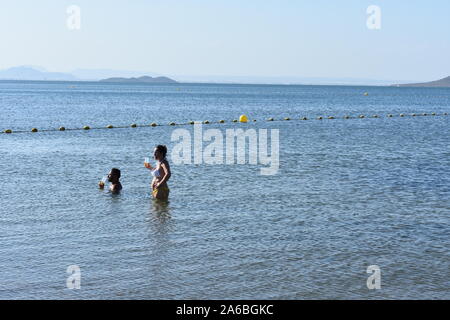 Man and woman enjoying a drink in the sea, Mar Menor, Murcia, Spain Stock Photo