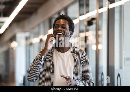 Excited African American employee talking on phone, receiving good news Stock Photo