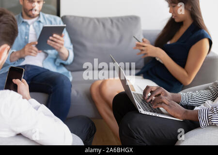 Diverse employees colleagues sitting in office room, using devices Stock Photo