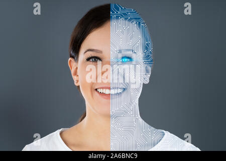 Close-up Of Two Faces Showing Woman And Robot Against Grey Background Stock Photo