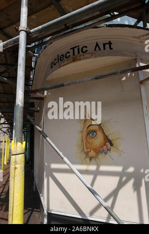 Graffiti of a woman peering through a hole the wall of art gallery Eclectic Art in Broad Street, Margate, Kent UK Stock Photo
