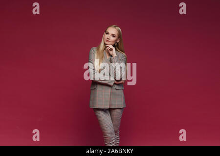 Young elegant businesswoman with professional makeup and in suit looking at the camera in the studio, isolated on pink background. Model girl in the Stock Photo