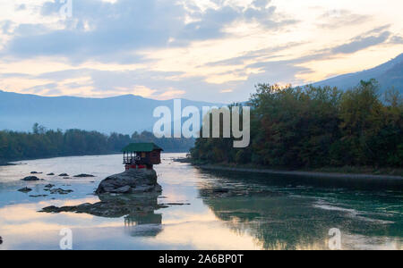 Tiny House Perched Atop a Rock in the Middle of a River. - image Stock Photo