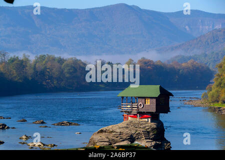 Tiny House Perched Atop a Rock in the Middle of a River. - image Stock Photo