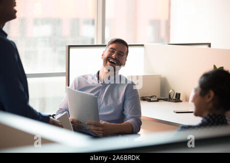 Millennial happy male businessman laughing with colleagues. Stock Photo