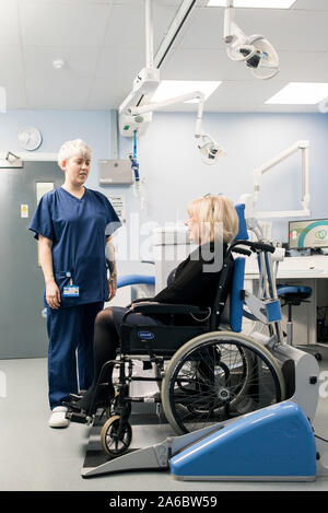 A dental nurse speaks to a disabled patient in a specialist wheelchair friendly dental chair Stock Photo