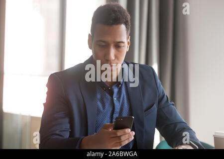 Unhappy african american businessman gets email on phone Stock Photo